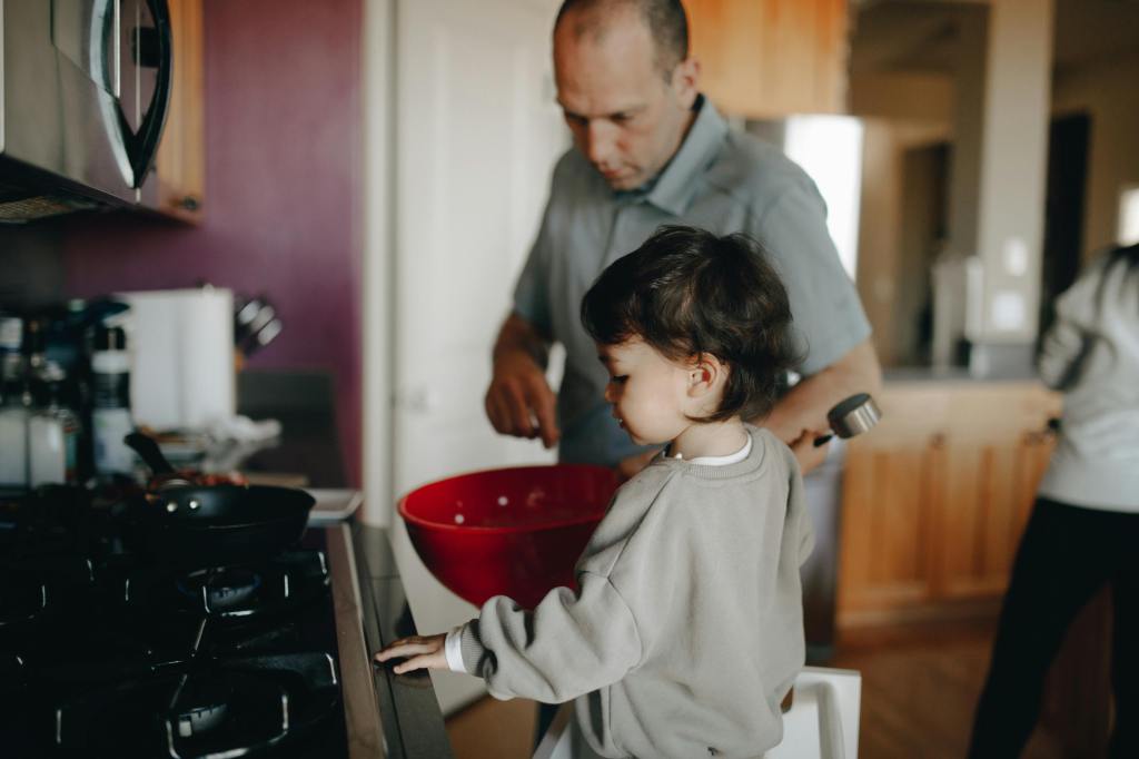 A father cooking in the kitchen with his young child observing and participating, showcasing the bonding experience in a family setting.