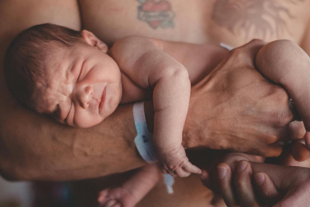 A close-up image of a father holding a newborn baby in his arms, showcasing a moment of tenderness and connection.